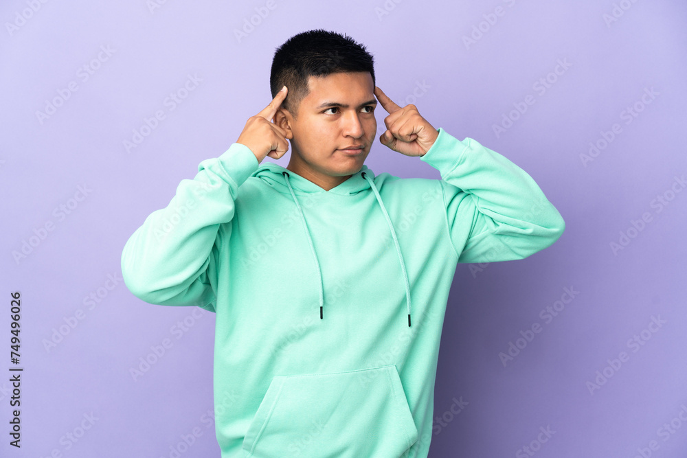 Young Ecuadorian man isolated on purple background having doubts and thinking Young Ecuadorian man isolated on purple background having doubts and thinking