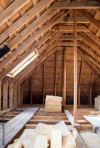 Insulating the roof of a house. Bales of fiberglass are laid out in the attic.