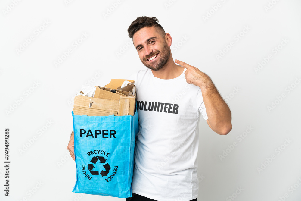 Caucasian man holding a recycling bag full of paper to recycle isolated on white background giving a thumbs up gesture Caucasian man holding a recycling bag full of paper to recycle isolated on white background giving a thumbs up gesture