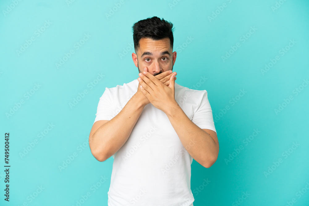 Young caucasian man isolated on blue background covering mouth with hands Young caucasian man isolated on blue background covering mouth with hands