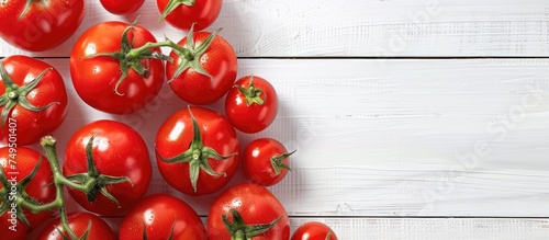 A top-down view of a collection of fresh, vibrant red tomatoes neatly arranged on a clean white wooden table. The tomatoes are ripe and ready for consumption, creating a visually appealing display © 2rogan