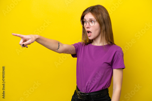 Young English woman isolated on yellow background pointing away