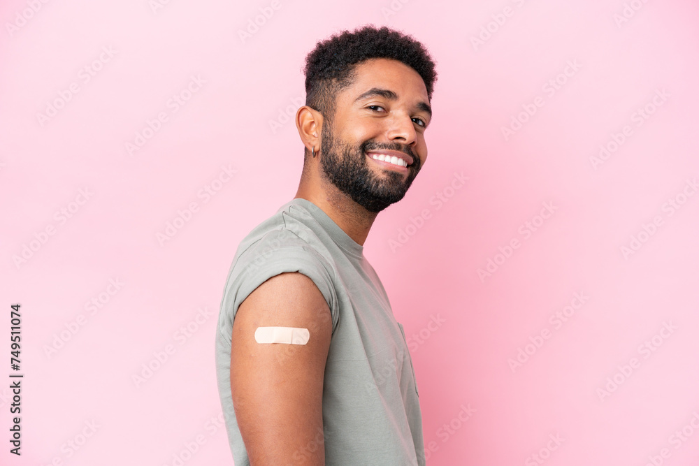 Young Brazilian man wearing a band aid isolated on pink background with happy expression Young Brazilian man wearing a band aid isolated on pink background with happy expression