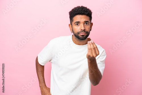 Young Brazilian man isolated on pink background making Italian gesture