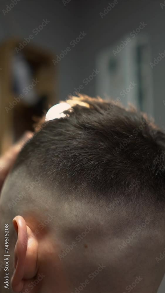 A barber man with a tattoo on his arm makes a haircut to a brunette guy in a barbershop, cuts his hair with a clipper close-up A barber man with a tattoo on his arm makes a haircut to a brunette guy in a barbershop, cuts his hair with a clipper close-up