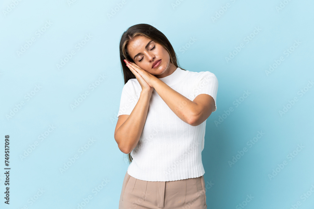 Young Uruguayan woman isolated on blue background making sleep gesture in dorable expression Young Uruguayan woman isolated on blue background making sleep gesture in dorable expression