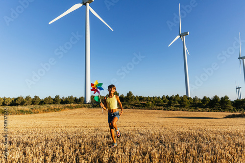 Energetic girl playing with pinwheel in agricultural field.