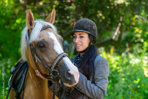 woman in a helmet holding a horse by the reins 