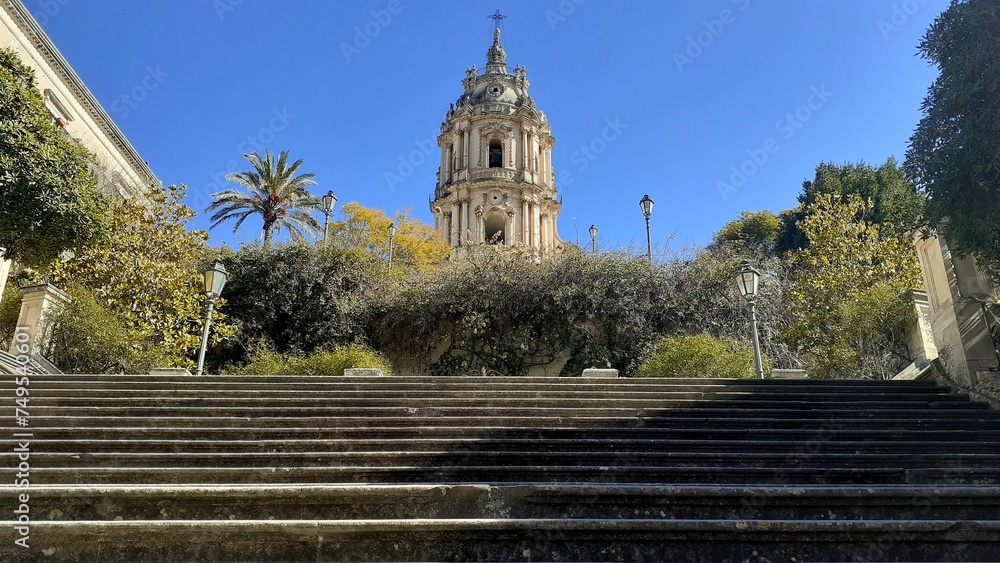 Fototapeta premium Il campanile del Duomo di San Giorgio a Modica che spunta tra gli alberi della scalinata.