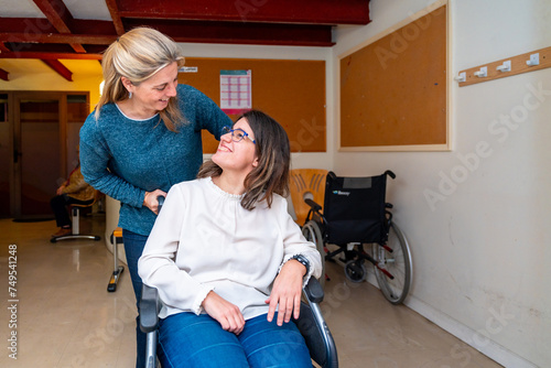 Caregiver pushing the wheelchair of a disabled woman photo