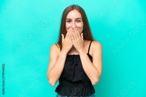 Young caucasian woman isolated on blue background happy and smiling covering mouth with hands