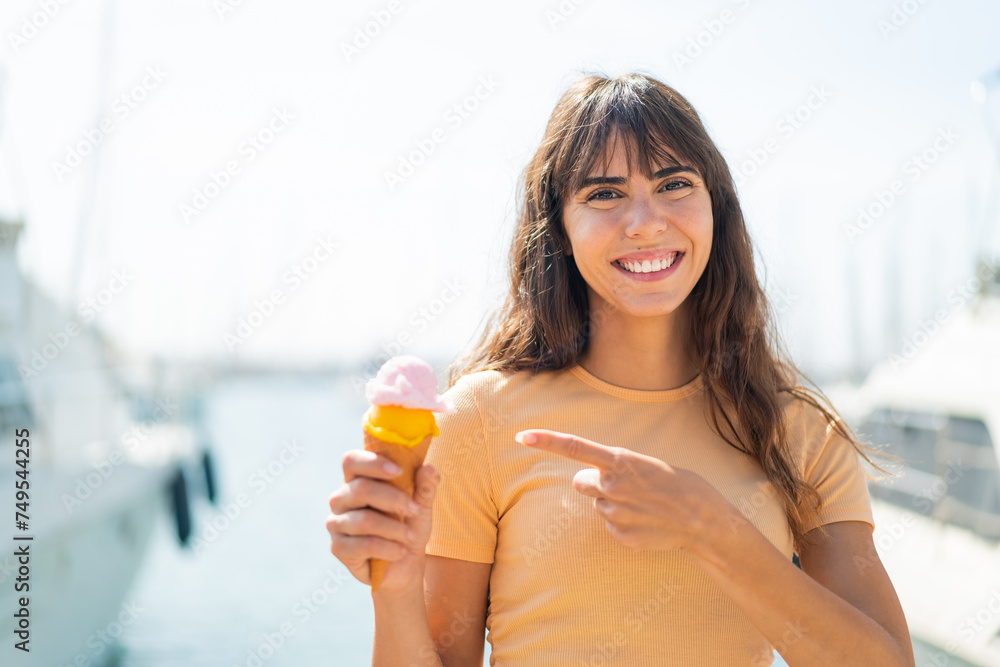 Young woman with a cornet ice cream at outdoors and pointing it Young woman with a cornet ice cream at outdoors and pointing it