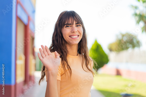 Foto Young woman at outdoors saluting with hand with happy expression