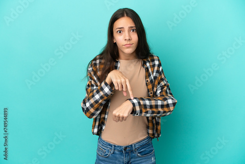 Young French woman isolated on blue background making the gesture of being late © luismolinero