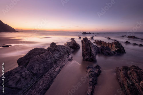 Horizontal view at sunset of the flysch of Barrika beach, Bizkaia, with a lot of sand between the rocks photo