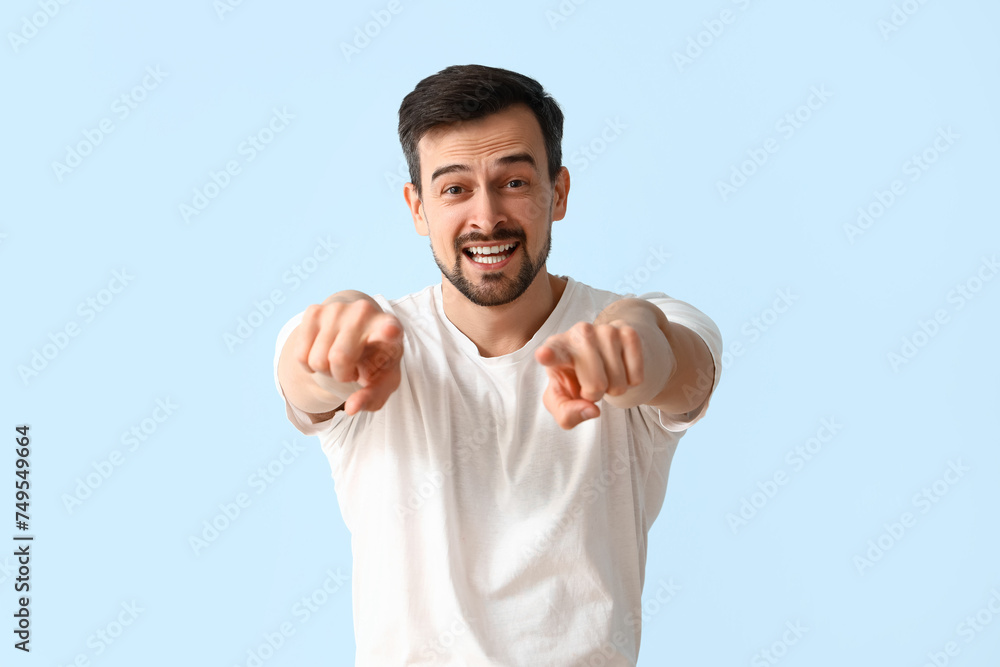 Handsome man pointing at viewer on blue background Handsome man pointing at viewer on blue background