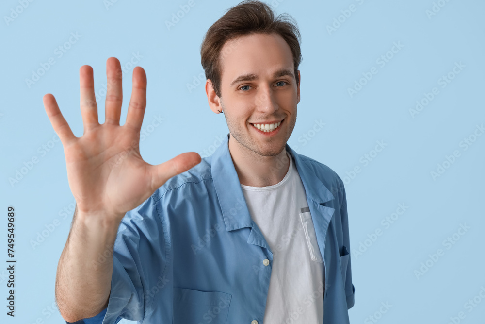 Young man showing hand on blue background, closeup Young man showing hand on blue background, closeup