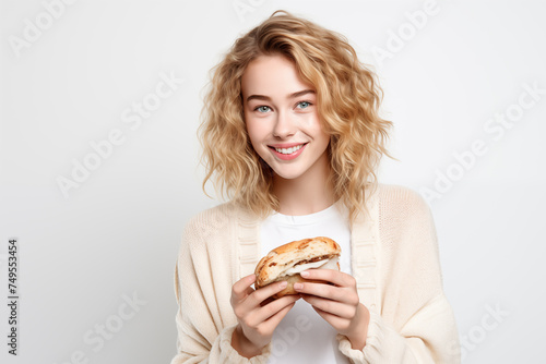 Young pretty blonde girl over isolated white background holding a sandwich