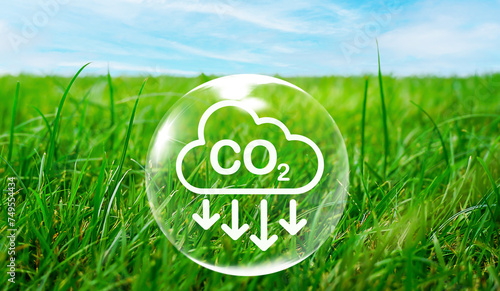 CO2 emission reduction icon inside of air bubble on green grass field in natural against blue sky background for concept in environmental, awareness of global warming, sustainable development ideas.