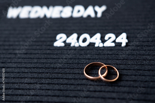 Rings of the newlyweds on the background of a Beautiful date for the wedding 04.24.2024 on a black lettobord