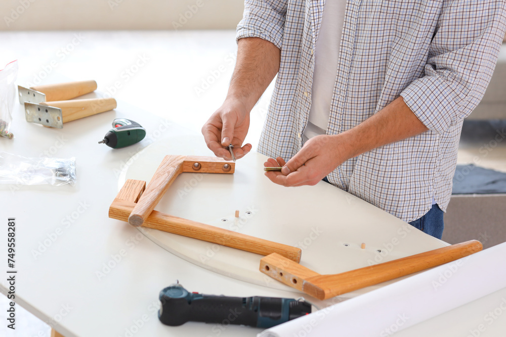 Young man with bolts assembling coffee table at home, closeup Young man with bolts assembling coffee table at home, closeup