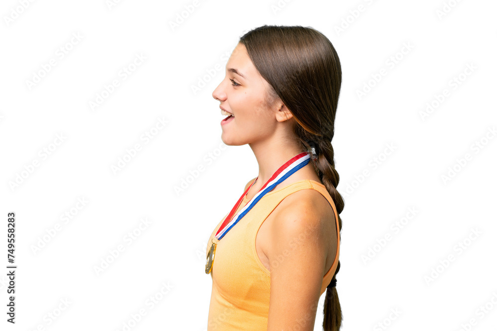 Teenager caucasian girl with medals over isolated background laughing in lateral position Teenager caucasian girl with medals over isolated background laughing in lateral position