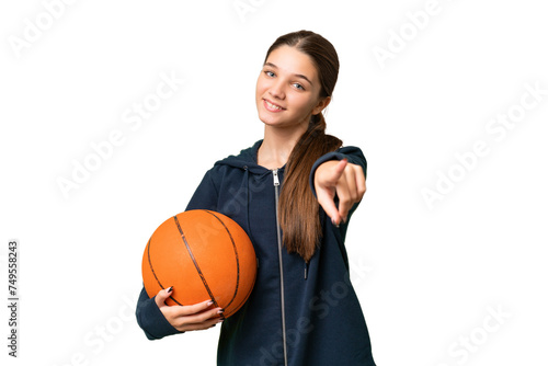Teenager caucasian girl playing basketball over isolated background pointing front with happy expression
