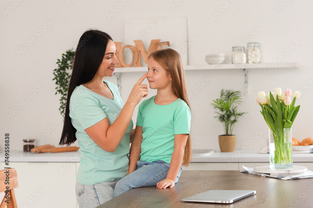 Happy mother touching her little daughter's nose in kitchen Happy mother touching her little daughter's nose in kitchen