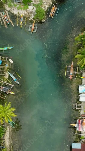 Tropical forest and Bogac Cold Spring in Surigao del Sur. Fishermens houses and boats over the water. Philippines. Vertical view. photo