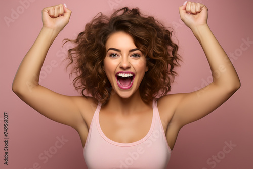 Euphoric winner. Portrait of a happy young woman with long curly hair on a pink background © missty