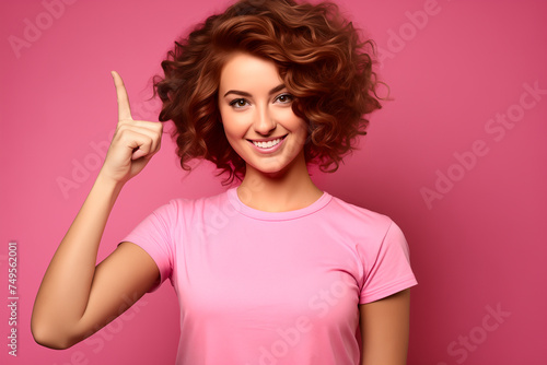 Woman surprise showing product. Beautiful girl with curly hair pointing to the side. Presenting your product. Isolated on pink background. Expressive facial expressions © missty