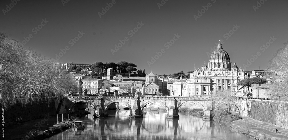 The River Tiber with historic building reflecting in the calm blue water, with St Peter's Basilica in the distance. It is Italy's third longest river.
