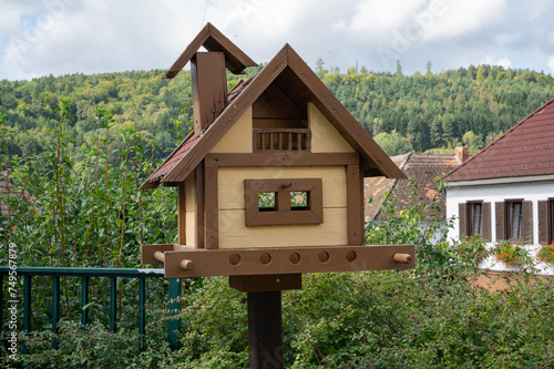Bird feeder in the form of a small wooden house against the backdrop of picturesque nature.