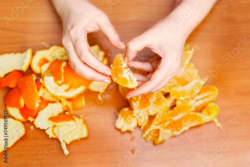 Top view of hands peeling oranges
