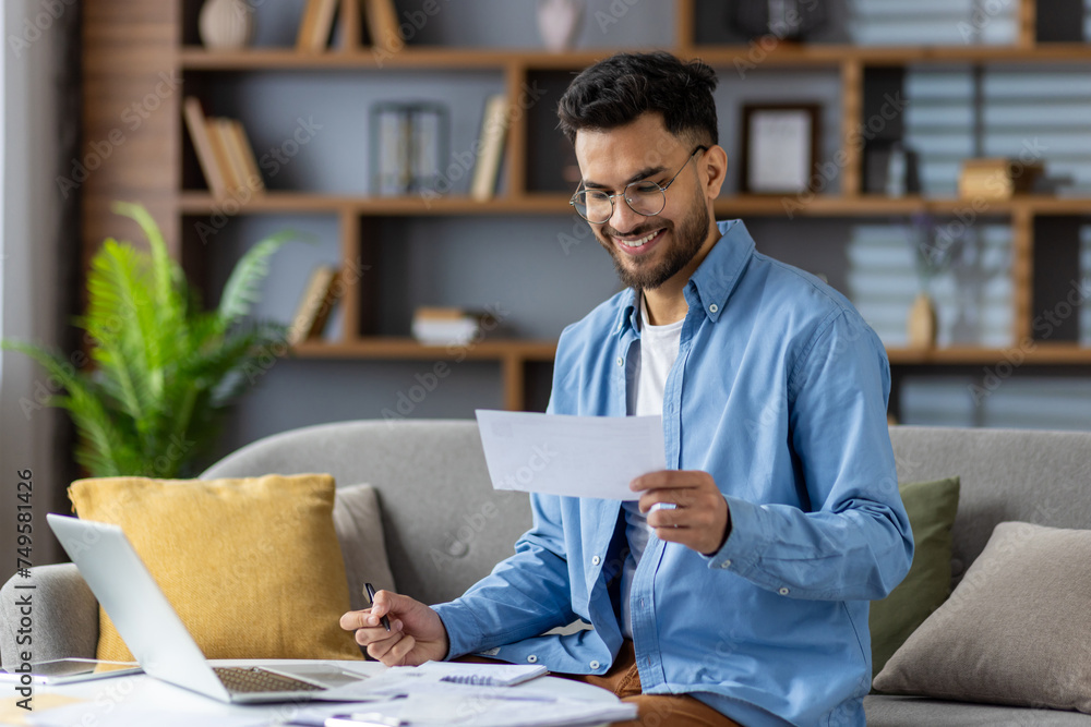 Indian man working from home, managing finances in a living room Indian man working from home, managing finances in a living room
