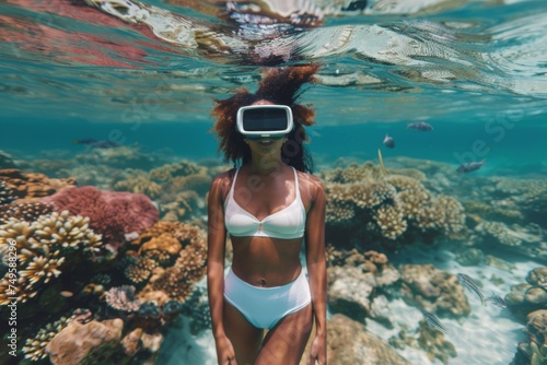A young woman stands submerged in clear water, donning a virtual reality headset, blending the marvels of technology with the beauty of a coral reef.