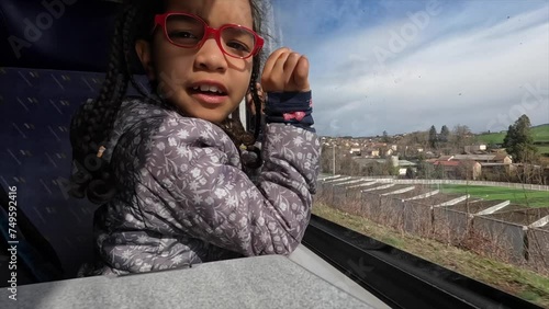 Little Latin girl enjoying train ride looking out window at scenery