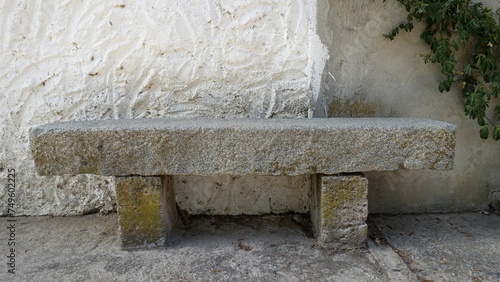 A light granite bench along the wall of an old abandoned house.