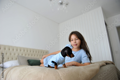 menina criança feliz a vontade em casa com cachorro de estimação filhote fofo de Dachshund  photo