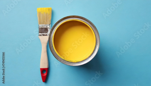 Metal can with yellow paint and brush. Flat lay on blue photo