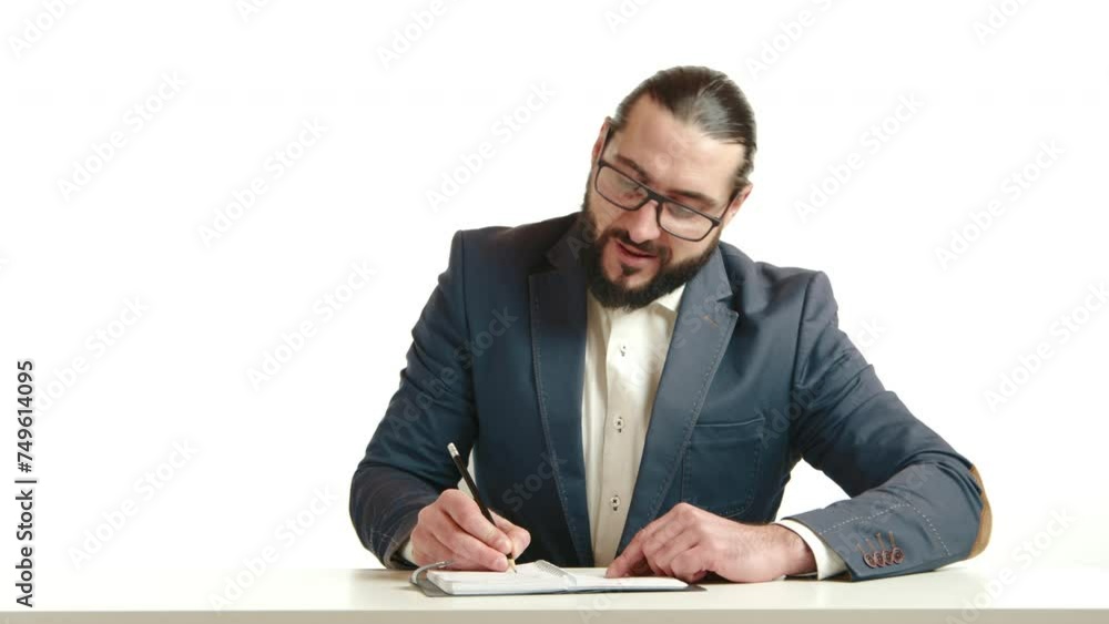 A serious businessman with glasses is engrossed in writing notes, demonstrating focus and attention to detail at his workplace on a white background. Camera 8K RAW. A serious businessman with glasses is engrossed in writing notes, demonstrating focus and attention to detail at his workplace on a white background. Camera 8K RAW.
