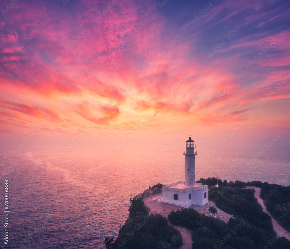 Lighthouse on the mountain peak at colorful sunset in summer