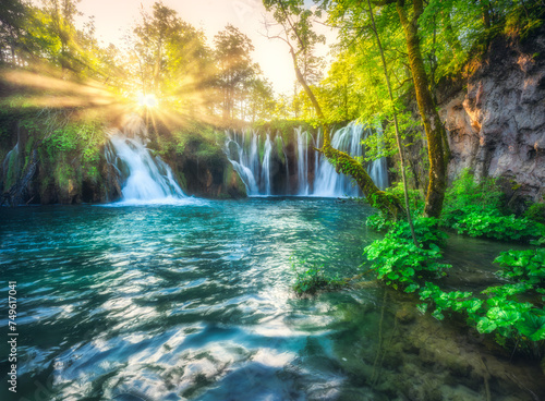 Waterfall in green forest in Plitvice Lakes  Croatia at sunset in summer. Colorful landscape with fall  blooming park  trees  water lilies  sunbeams  river in spring. Scenery. Park in woods. Nature 