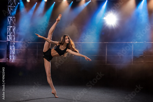 young performer of modern choreography dancing in the spotlights on a black background. © Maria Moroz