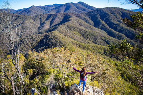 hiker girl admires the panorama of folded mountains from the summit of mount may; australian mountains in mount barney national park in queensland near gold coast and brisbane photo