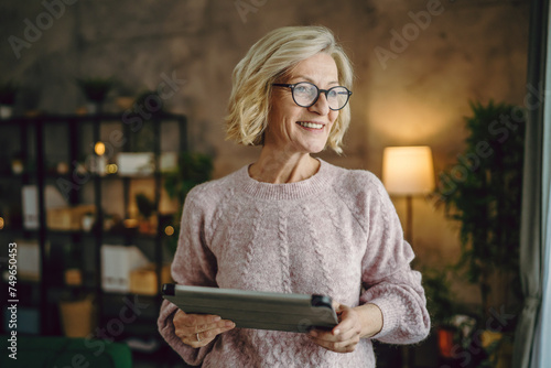 mature blonde woman with eyeglasses use digital tablet at home photo