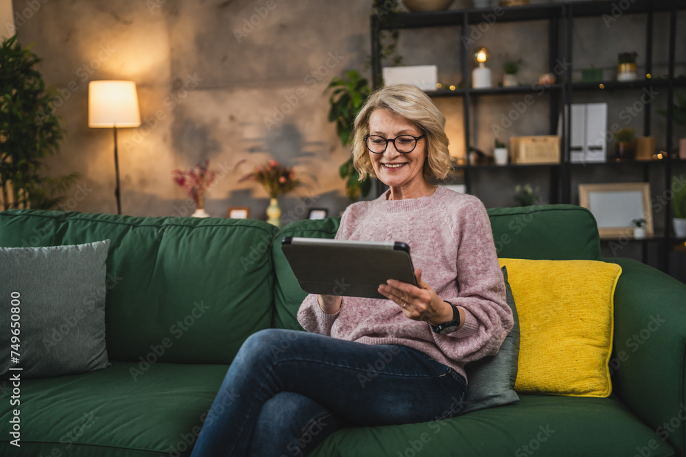 Obraz premium mature blonde woman with eyeglasses use digital tablet at home