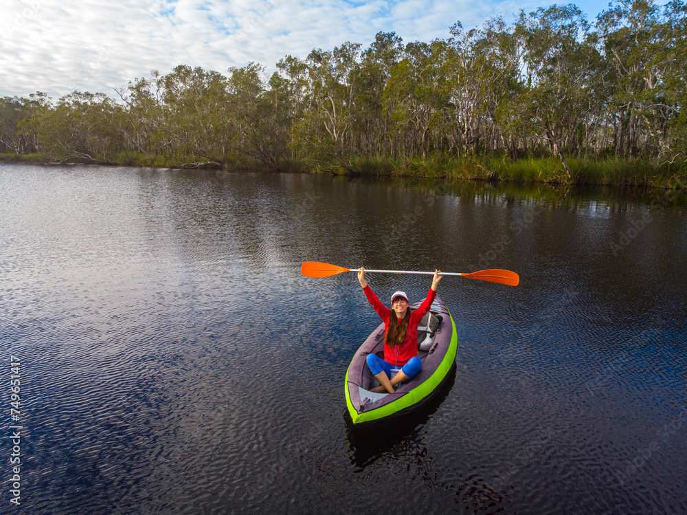 aerial view of adventurous girl paddling on an inflatable kayak through