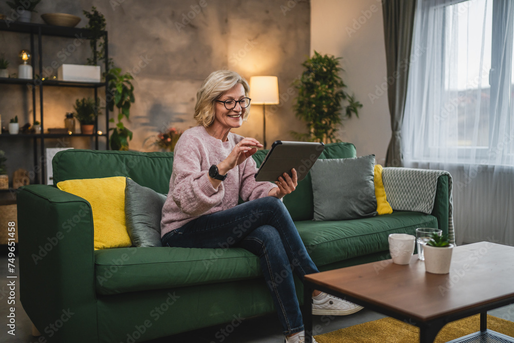Obraz premium mature blonde woman with eyeglasses use digital tablet at home