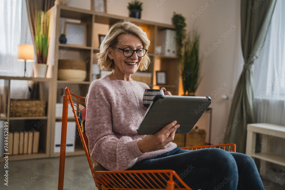 mature blonde woman with eyeglasses use digital tablet at home mature blonde woman with eyeglasses use digital tablet at home